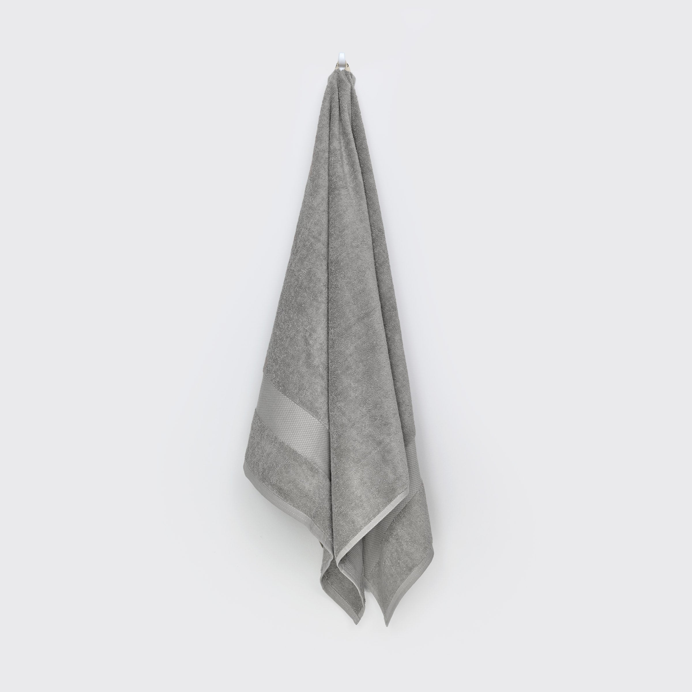 organic-cotton-bath-towel-in-stone-colour-hanging-on-a-wall-by-sojao