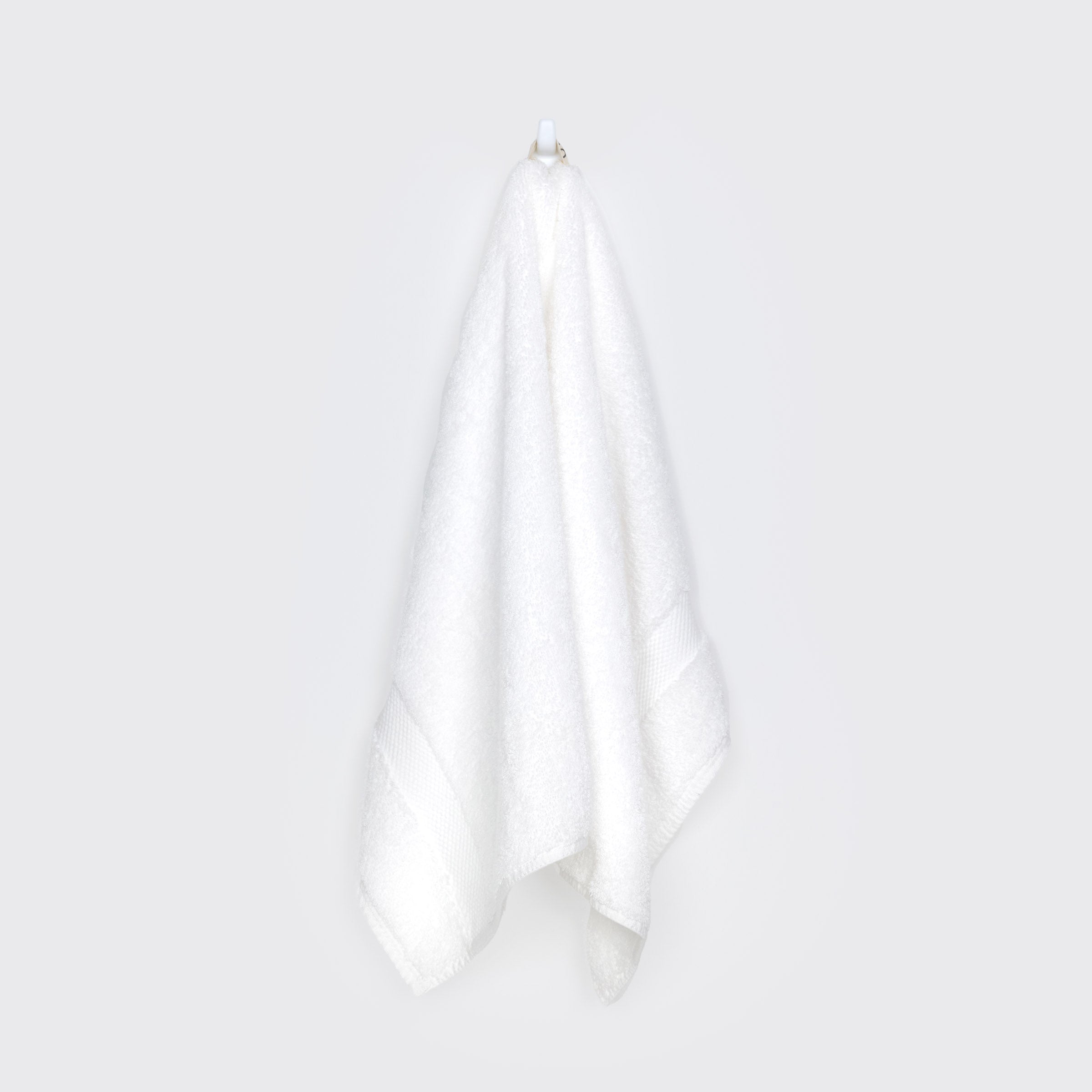 organic-cotton-hand-towel-in-white-colour-hanging-on-a-wall-by-sojao