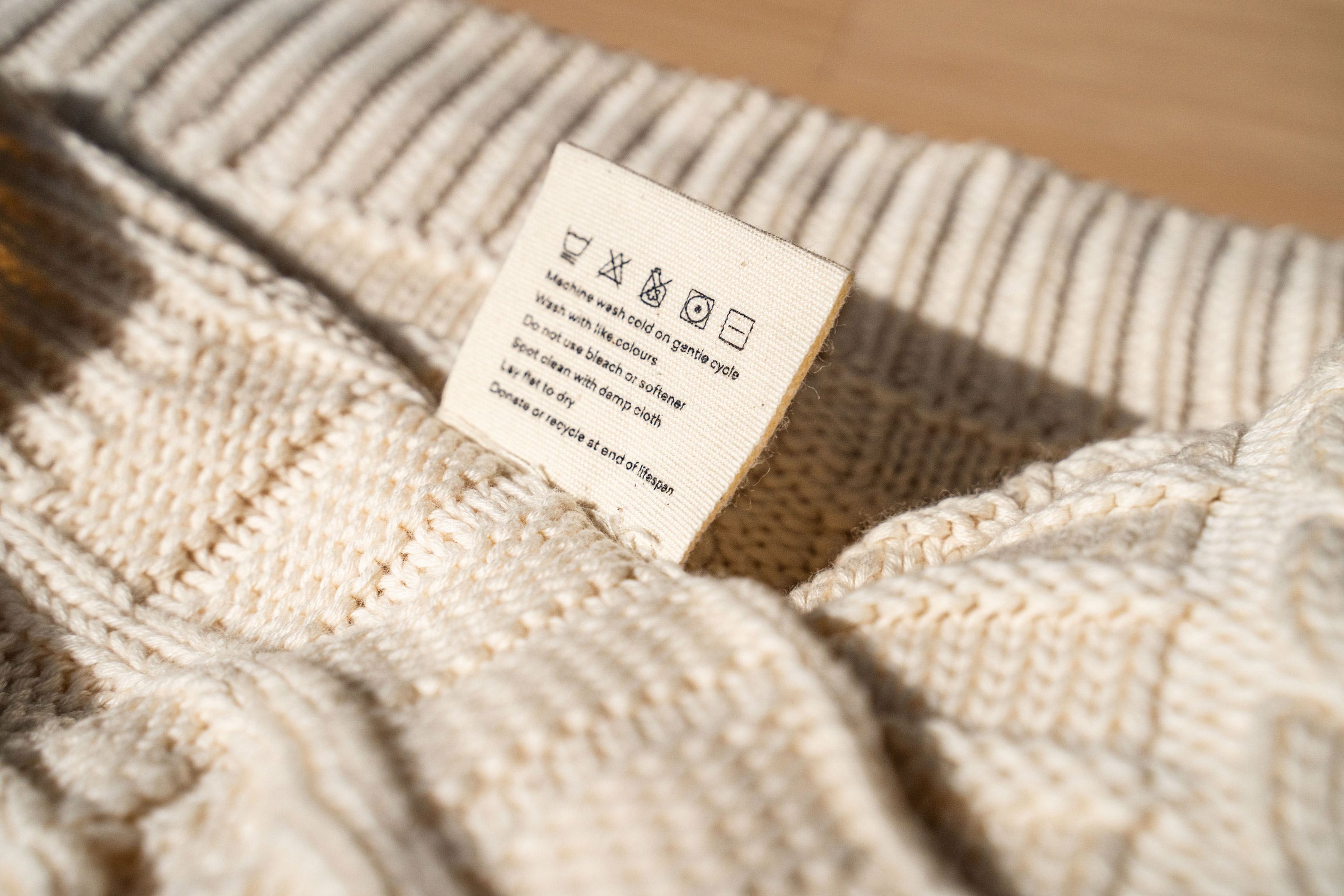organic-cotton-cable-knit-throw-detail-in-ivory-colour-with-wash-care-tag-by-sojao