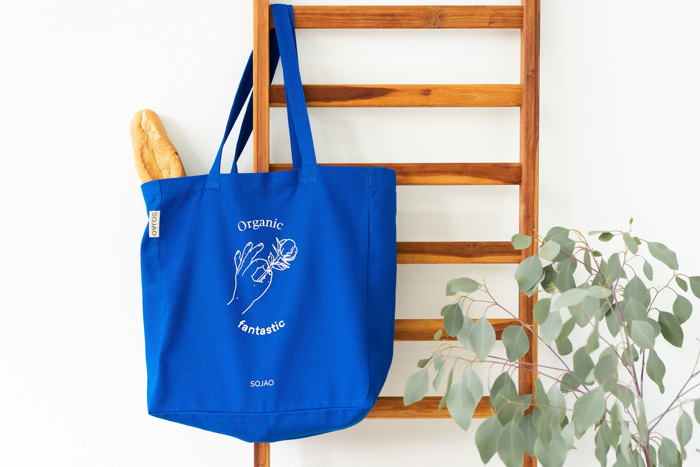 organic-cotton-tote-bag-in-blue-colour-hanging-on-a-wooden-ladder-by-sojao